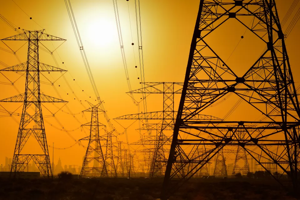 Large power towers sillhouetted against an orange sky